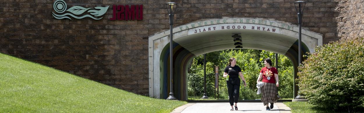 Two staff members walking on the trail on campus