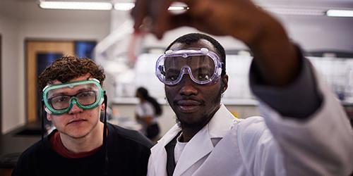 两个学生在科学实验室拿着烧杯